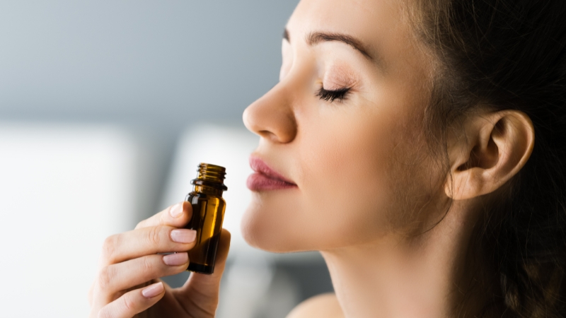 Woman smelling essential oil from a small amber bottle during an aromatherapy session