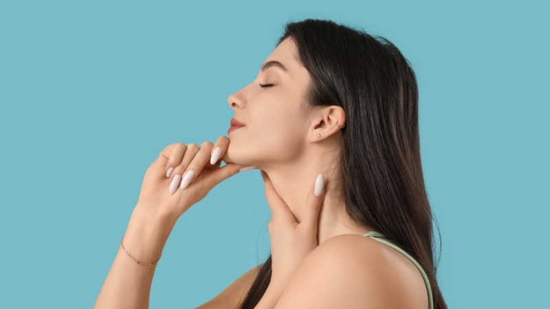 Woman doing face exercises by lifting her head and touching her neck