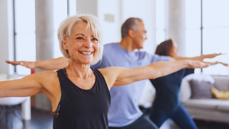 Older adults in a group class practice balance and strength exercises, showing real-life examples of fitness and food over 70 in action