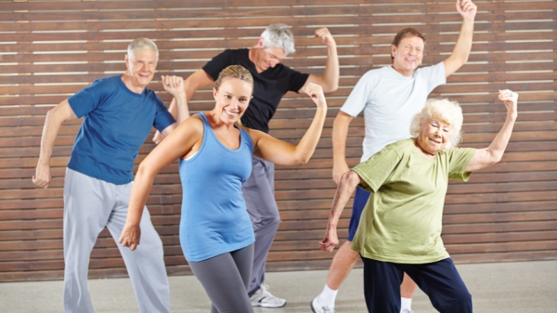 A group of older adults exercises with a trainer, showing how support and routine help maintain health and independence