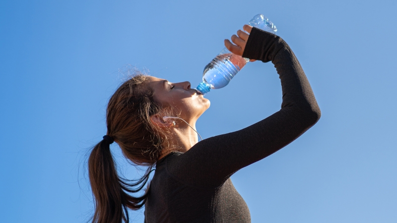 Woman in workout gear drinking water after exercise to rehydrate and refresh her body