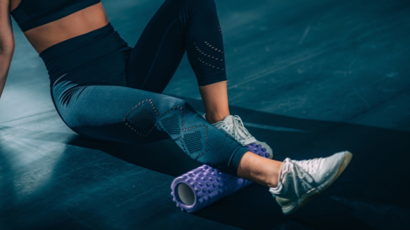 A woman using muscle rollers on her legs to reduce soreness and improve flexibility after a workout