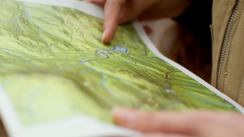 Person using a topographic map to plan route, showing key navigation tools for mountain treks