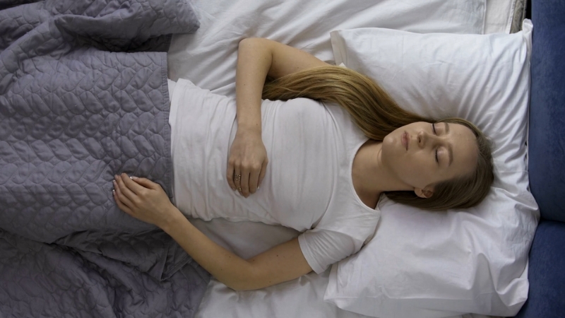 Woman sleeping on her back with a straight posture and a supportive pillow to maintain proper neck alignment