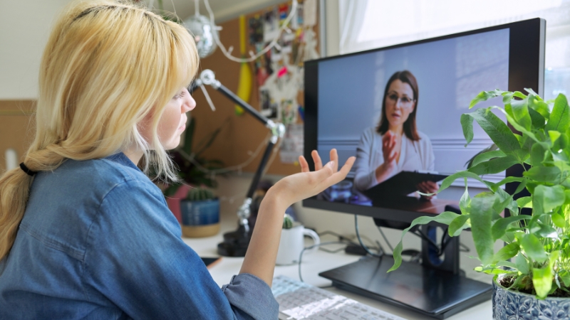 A woman speaks with her coach during an online video call focused on fitness and behavior change support