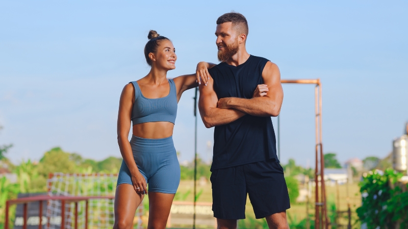 Man and woman in workout clothes smiling after training outdoors, showing how planning ahead supports fitness while traveling