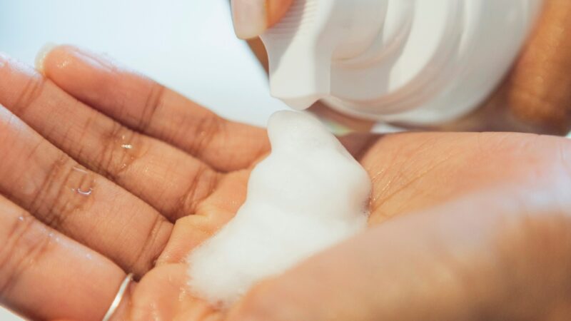 A close-up of a person dispensing foaming cleanser into their hand before starting a skincare routine