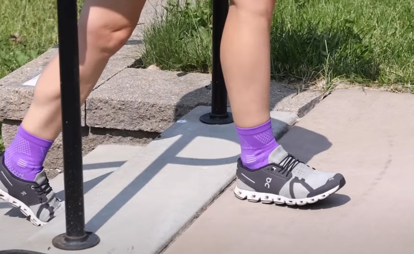 A person ascends steps, showcasing supportive athletic footwear and vibrant purple socks