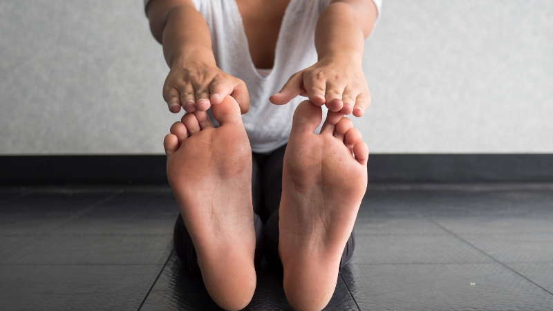 Person doing seated stretches on the floor as part of a nighttime routine to support muscle recovery