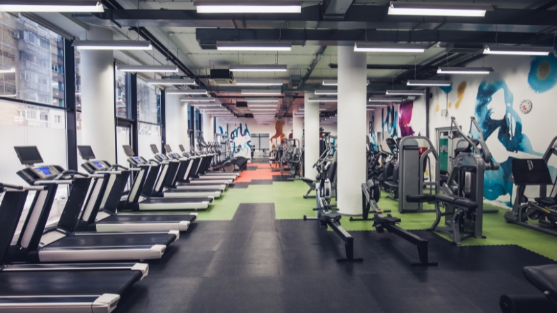 A modern gym with treadmills and strength machines arranged in zones shows design tips for creating an open and comfortable workout space