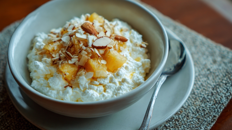 Cottage cheese topped with pineapple chunks and sliced almonds in a bowl