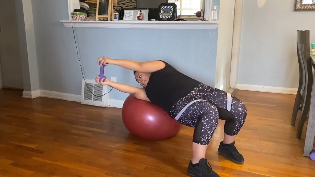 Woman performing oblique twists on a stability ball with a dumbbell