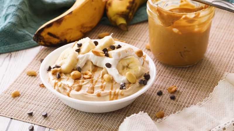 Greek yogurt topped with banana, peanut butter, nuts, and chocolate chips