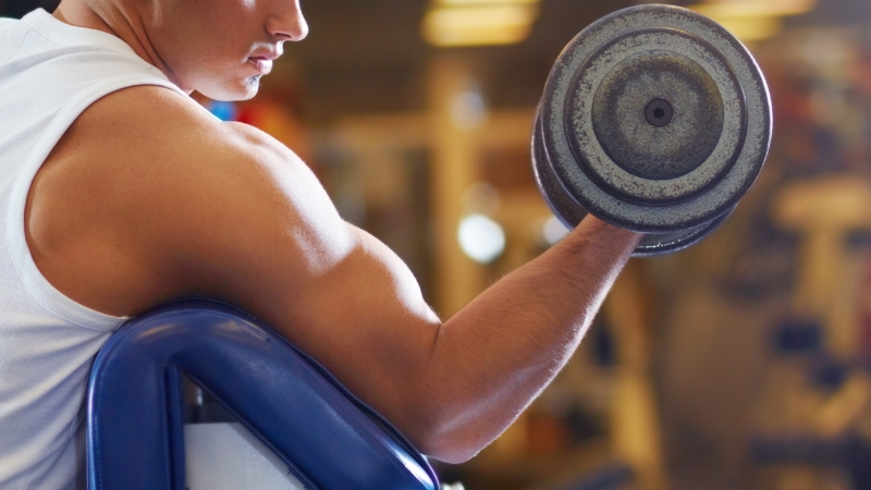 A man lifts a heavy dumbbell, showing strength supported by healthy testosterone levels
