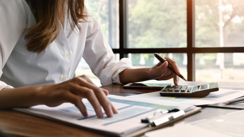 A person uses a calculator and reviews financial documents, showing why new gym owners must plan finances before opening