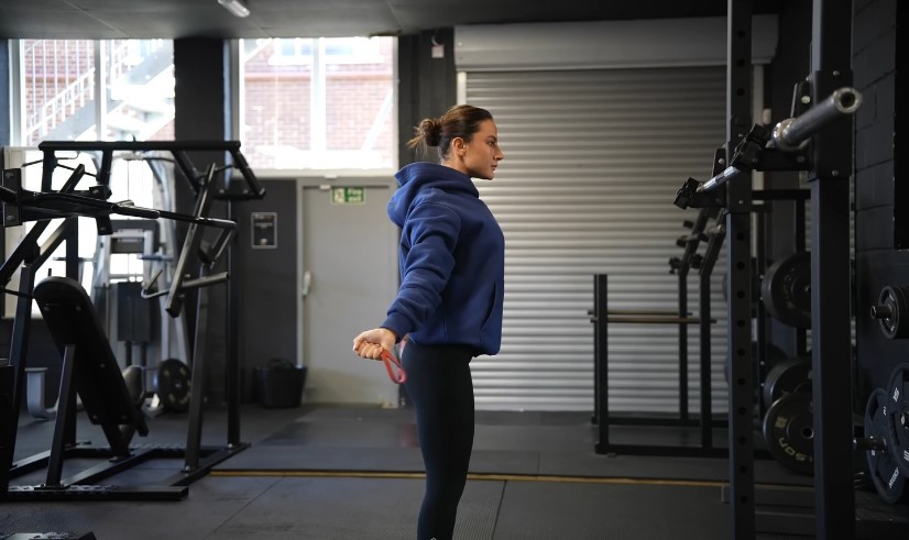 A woman in a blue hoodie performs an exercise in a gym