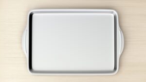 An empty rectangular baking pan with handles placed on a light wooden surface