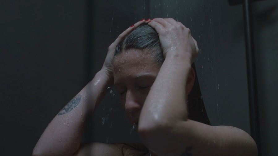 Close-up of a person's hands washing their hair in a shower
