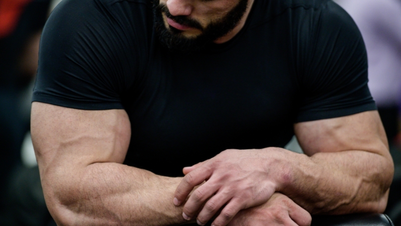 A man with muscular arms shows how testosterone supports muscle growth