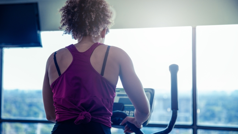 Woman on a cardio machine wearing a moisture-wicking tank top and supportive sports bra