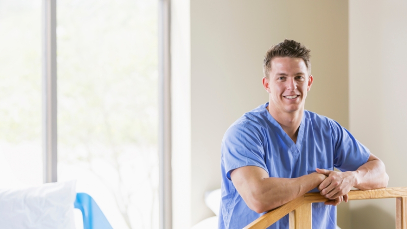 A smiling healthcare professional in blue scrubs stands ready to help patients manage sciatic pain