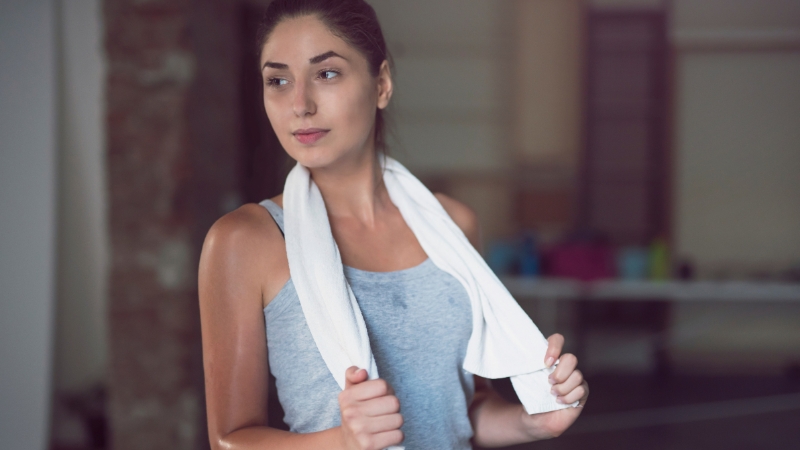Woman glowing after exercise, towel around her neck, showing the effect of smart post-workout rituals