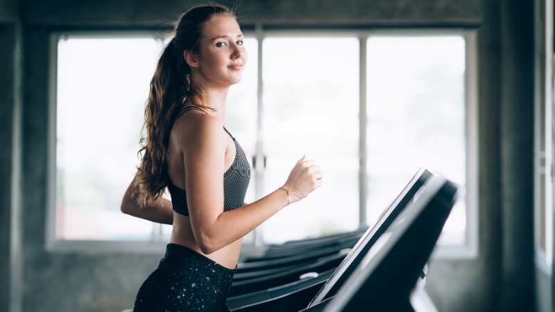 Woman on a treadmill during a workout, illustrating cardio before or after weight training