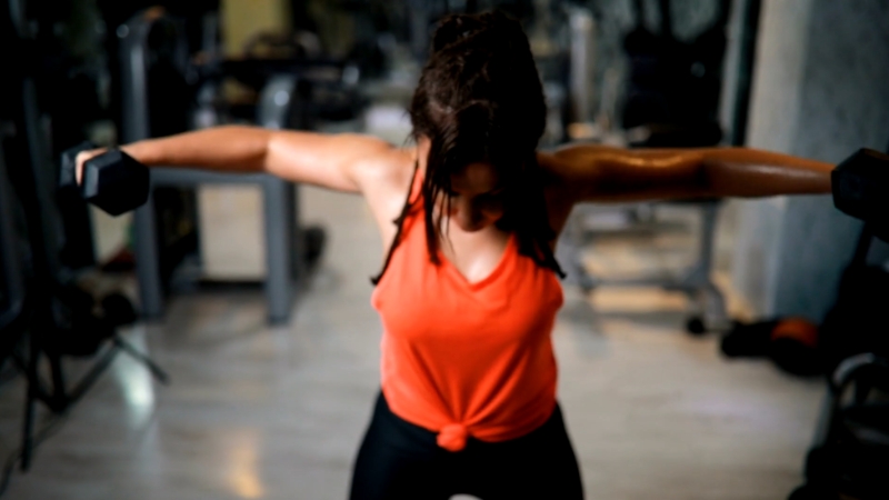 A woman lifts dumbbells in the gym