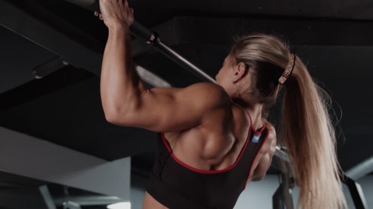 Training and self-esteem shown through a woman building strength with pull-ups in the gym