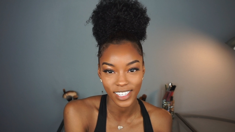 A woman with curly hair styled in a high pineapple bun, a secure choice for workouts