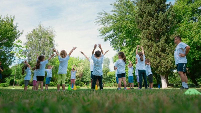 Children exercising outdoors with a coach, showing special considerations for youth training in nature
