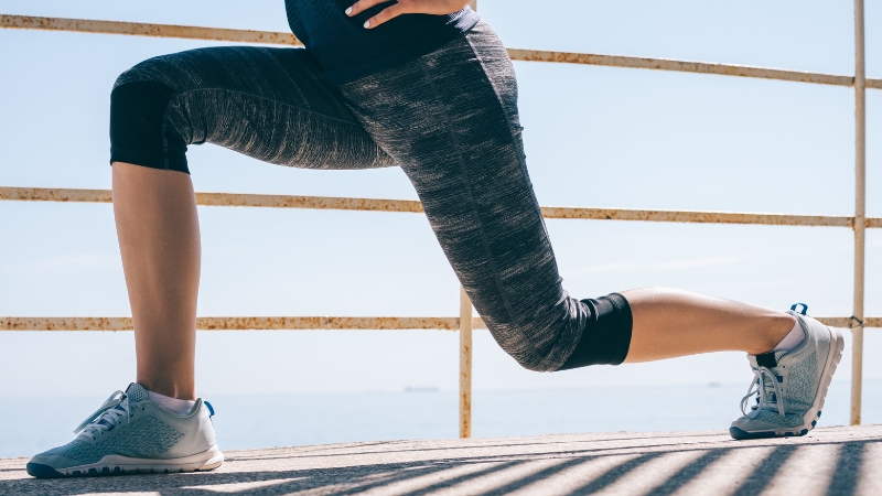 A person performing lunges as part of a total body circuit training workout outdoors