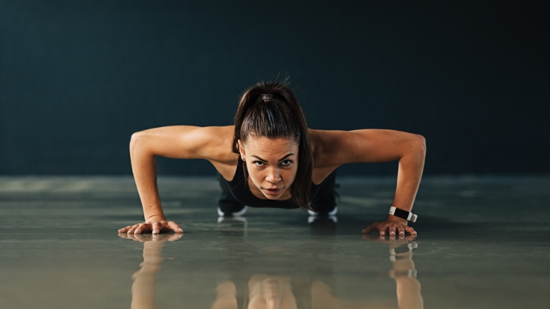 A woman doing push-ups on the floor as part of a total body strength workout