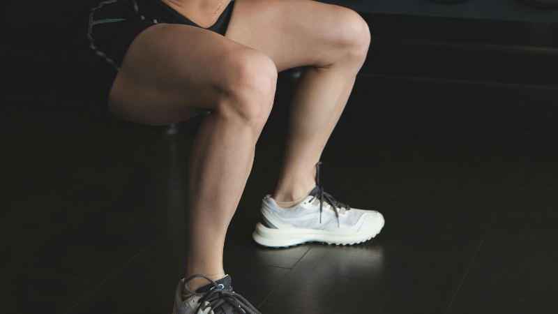A person performs a lower-body strength exercise in a gym, focusing on leg muscles while squatting