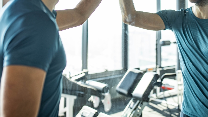 A man in a gym looking at his reflection during a workout