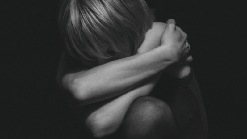 A woman curled up with her arms wrapped around herself