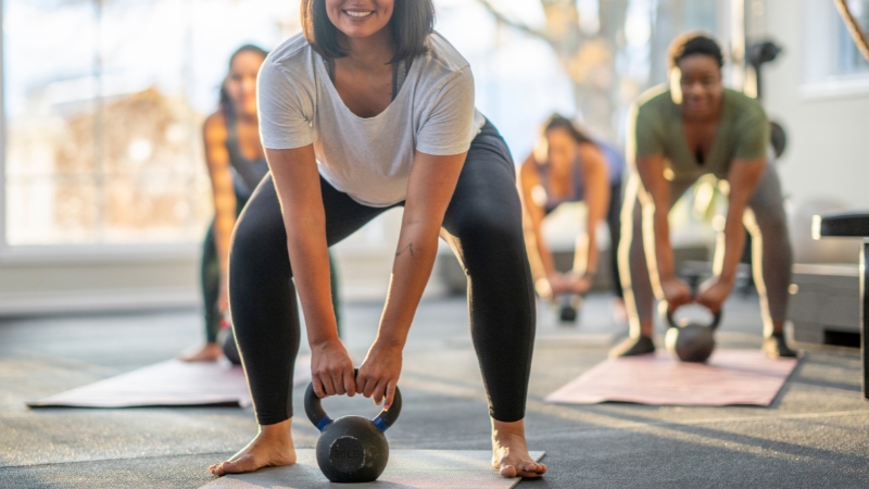 Group of people lift kettlebells together in a supportive workout class
