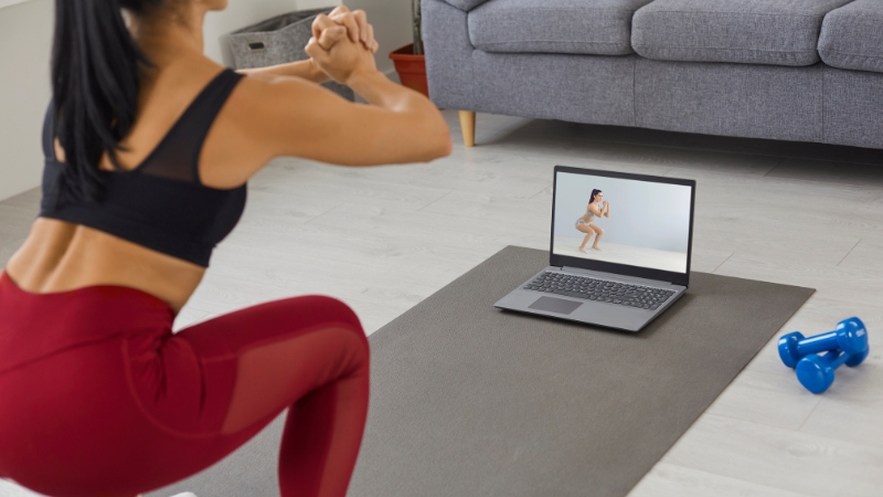 Person follow a workout video on a laptop at home during an online fitness course