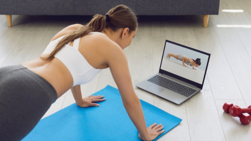 Person follow a laptop workout at home on a yoga mat during an online fitness course