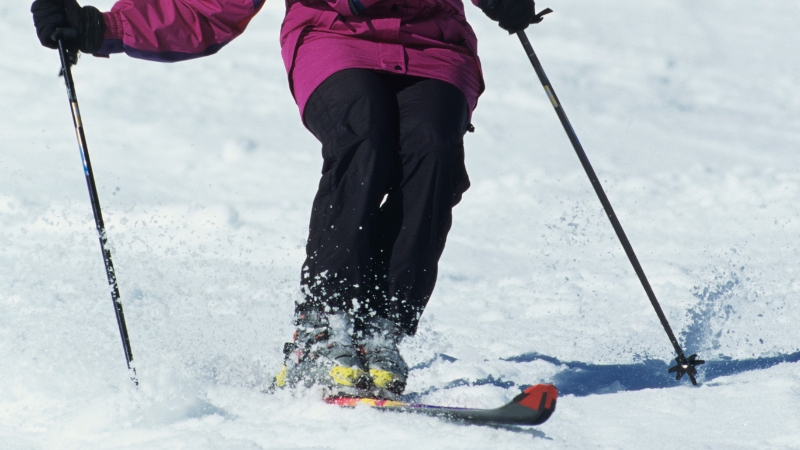 A skier carves through soft snow, showing the leg control required in alpine turns