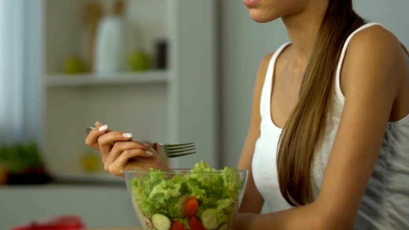 A woman eats a fresh salad as part of a balanced diet while using tirzepatide