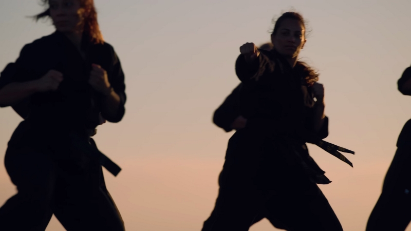 Women practice Taekwondo strikes outdoors at sunset