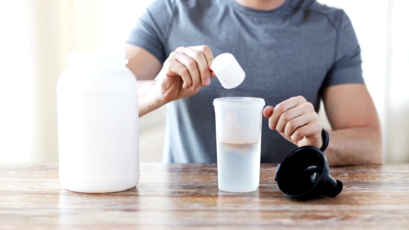 Man preparing a protein shake to compare whey vs plant-based protein digestibility and tolerabilit
