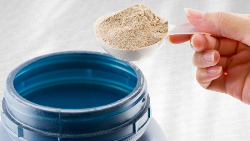 Scoop of protein powder being added to a container