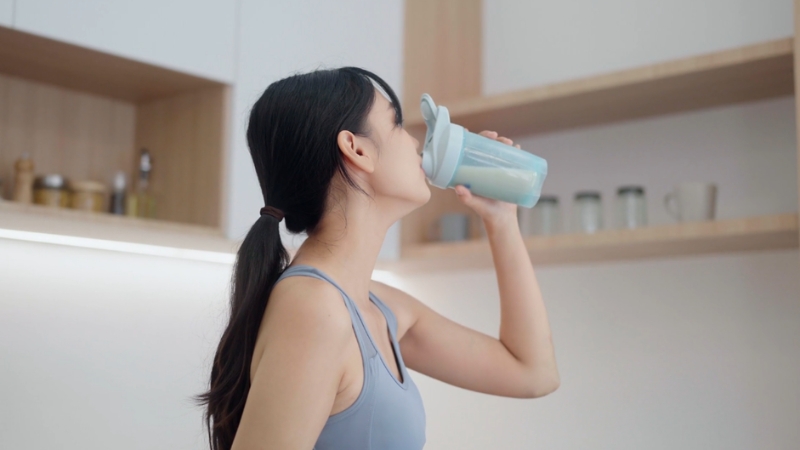 Woman drinking a protein shake after workout to illustrate whey vs plant-based protein