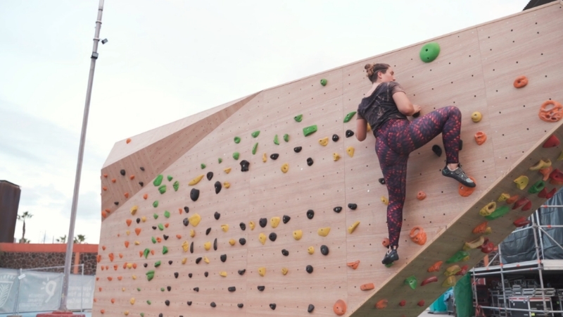 Person climbing an outdoor wall using arms, legs, and core for support