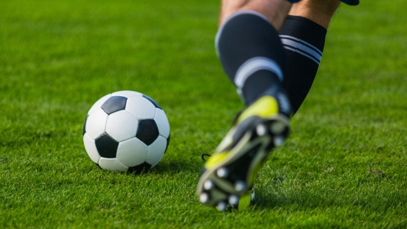 Football player dribbles a soccer ball on grass during a training session