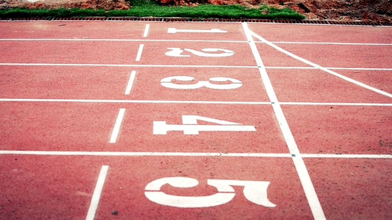 Red running track lanes marked with white numbers and finish lines at an athletics stadium