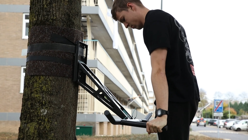 Man perform dips on a pull-up and dip station secured to a tree in an outdoor setting