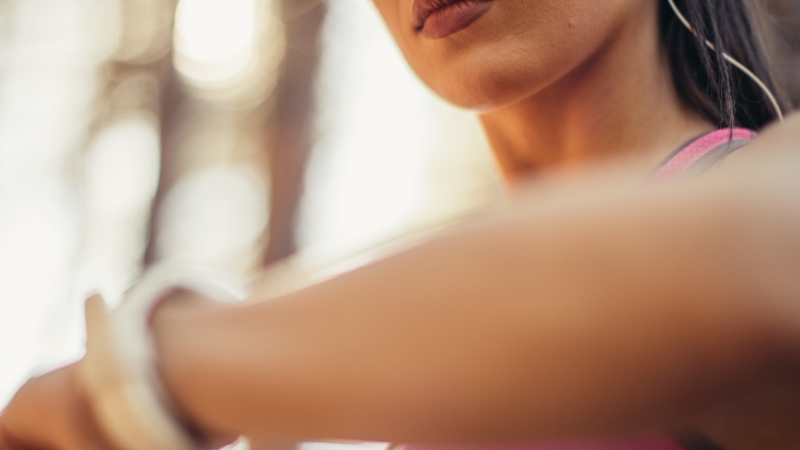 Woman check wristwatch before workout to time training around fasting window